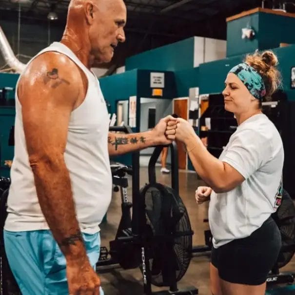 Coach Erin Patchey guiding a client through a workout in a gym environment.